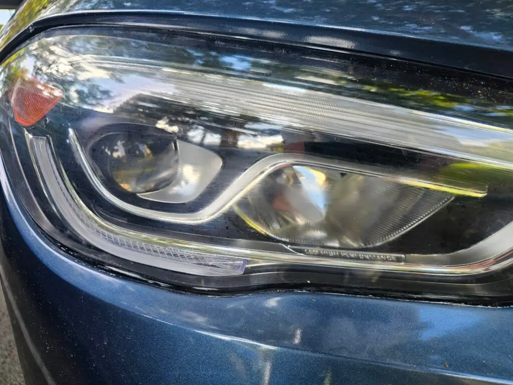 Close-up image of a faded and cloudy car headlight on a vehicle in Pembroke Park, Florida. The headlight lens appears dull and foggy, likely due to oxidation or wear over time, and needs a headlight restoration.